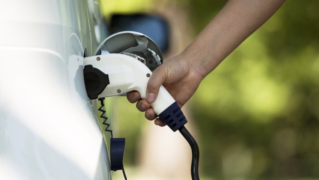 Person putting charging nozzle in electric car